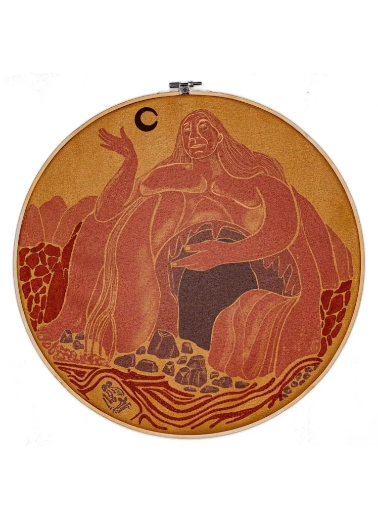 Ilustración digital impresa sobre lienzo e intervenida con bordado. La imagen muestra una cueva con el rostro de ShanidarZ. La cueva es un vientre también.